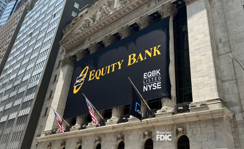 The front of the New York Stock Exchange, with a black banner bearing the Equity Bank logo and white text that reads 